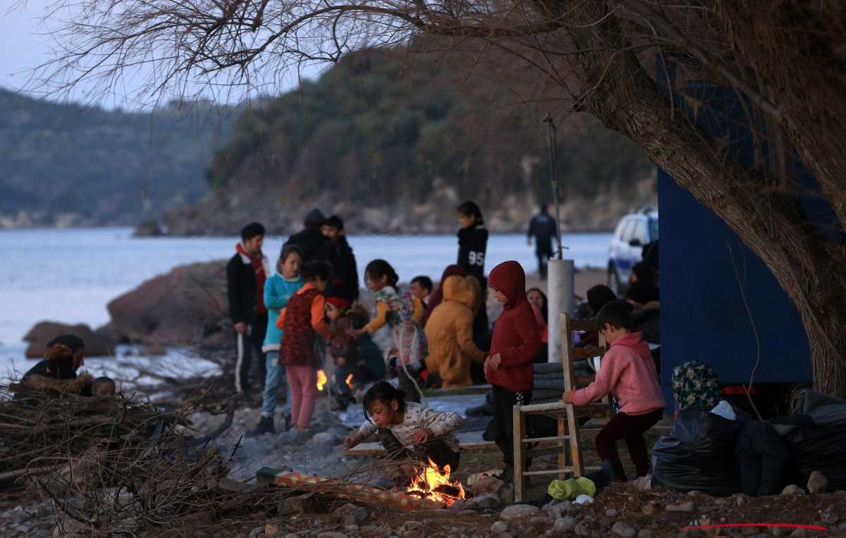 vluchtelingen zitten rond kampvuur