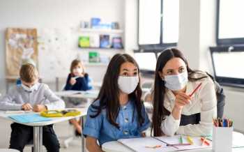 leerkracht en leerling met mondmasker